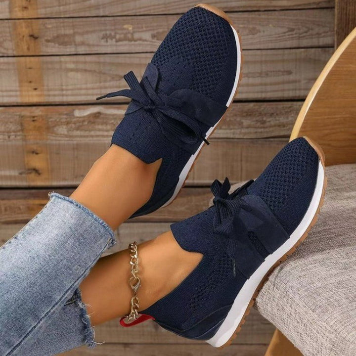 Baskets plates pour femme bleu marine en maille respirante avec lacets, empiècements suédés, semelle blanche et extérieure gomme, look moderne et confortable.