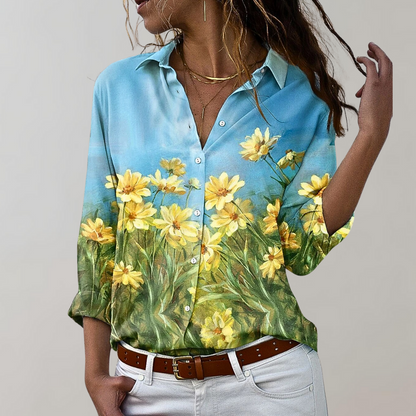 Chemise élégante avec imprimé de fleurs jaunes sur fond bleu et vert, col classique et manches longues, style raffiné et féminin.